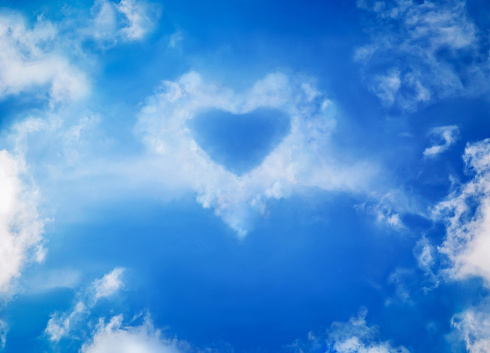 Blue sky with white fluffy cirrus clouds in the form of a heart, soft focus. Heavenly clouds look like a heart. Love, lovers, imagination, Valentine's Day, Women's Day, Mother's Day concept. Copy space.