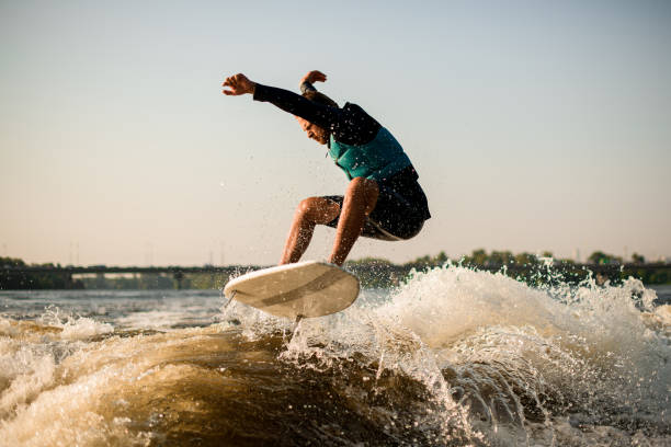 istock athletic man energetically jumping on a wakesurf board over river waves 1394423825