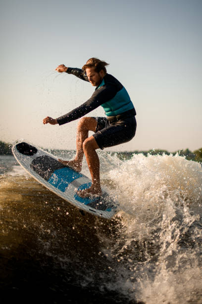 istock sports man skillfully makes jump with wakesurf board over the wave 1394425969