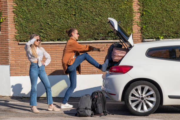 verzweifeltes junges paar, das versucht, alle koffer im auto zu bekommen, um auf einen roadtrip für die frühlingsferien zu gehen - auto kofferraum stock-fotos und bilder