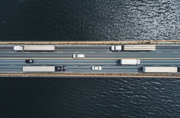 Semi Trucks on Bridge Aerial drone view of semi trucks on suspension bridge. Composite image. semi trailer stock pictures, royalty-free photos & images