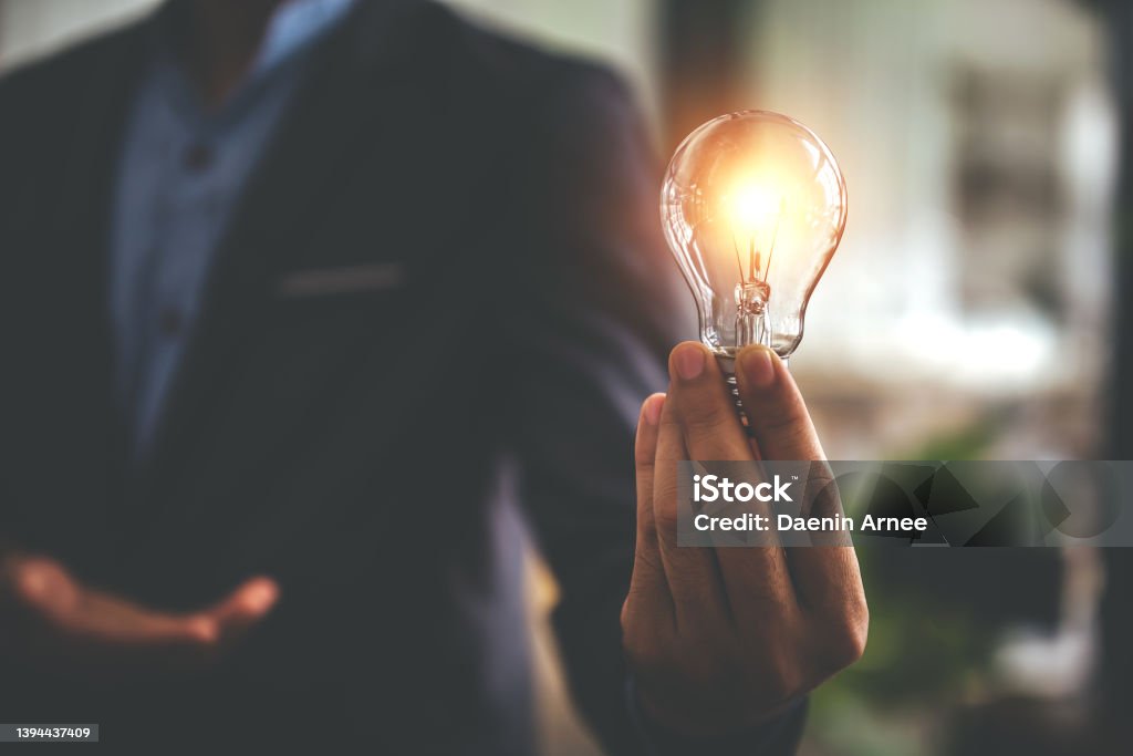Hand holding a light bulb. Innovative concept with inspiration and energy saving concept. Businessman holding a light bulb. Innovative concept with inspiration and energy saving concept. Light Bulb Stock Photo