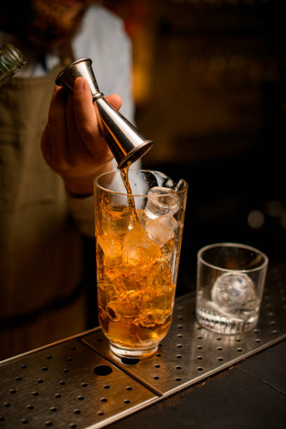 istock hand of the bartender pours beverage from jigger into mixing cup with ice 1394442578