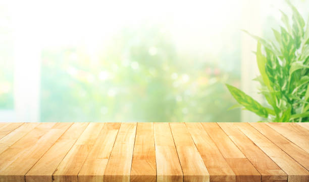istock Empty wood table top on blur abstract green garden from window kitchen in the morning. 1394445190