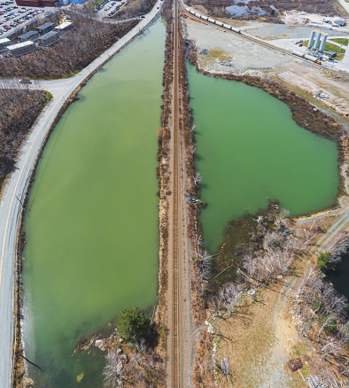 Aerial drone view of a sediment retention pond divided by railroad tracks.
