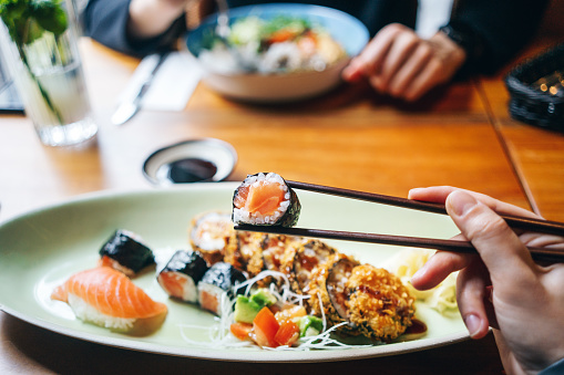 Personal perspective shot of a woman eating salmon sushi rolls