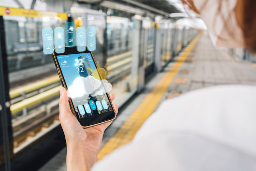 Women using smartphone with Augmented reality weather apps and virtual reality interfaces in the real-world, commuter and transportation concept, smart city concept, Weather forecasts and meteorology report