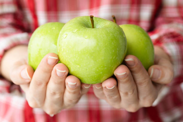 Young woman holding green apples.