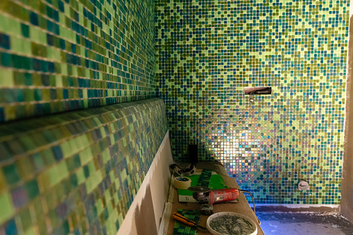 Installation of mosaic tiles. Modern green mosaic, sauna interior design. Hammam interior design.