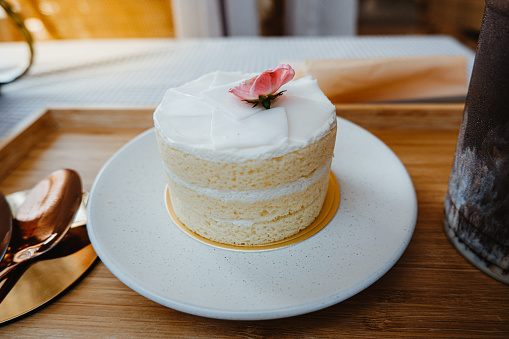Close-up shot, A Rose flower decorate topping on the Soft white cake cream in the white plate.