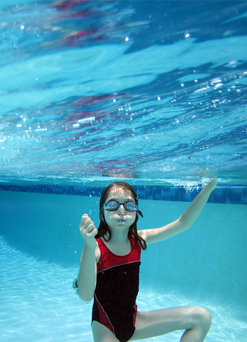 Close up underwater view of elementary age girl swimming in swimming pool in Florida