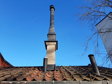 Close up of Prefabricated building roof with industrial black chimney under blue sky. Architecture and construction detail.