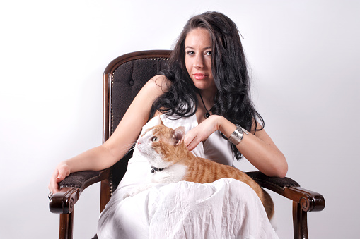 Beautiful white happy woman and cute cat sitting on armchair