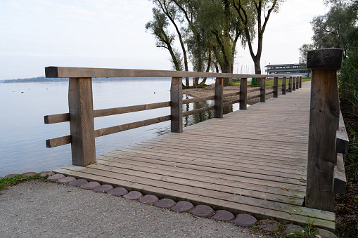 Wooden footbridge for pedestrians on a lake in a autumn morning