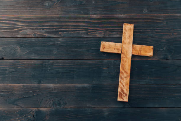 istock Christian cross on wooden background 1394480720