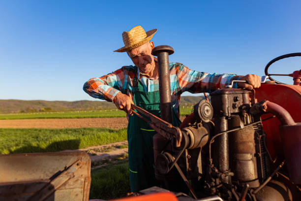 istock Senior farmer with a hat on his head fixing tractor 1394481620