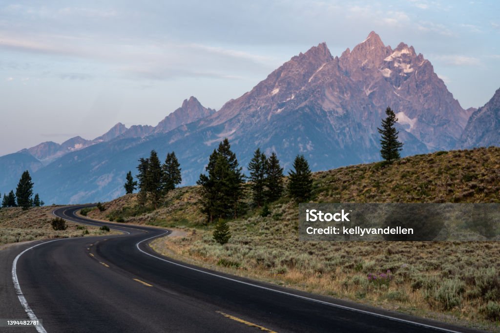 Winding Road Climbs Hillside in front of the Tetons Winding Road Climbs Hillside in front of the Teton Range Road Stock Photo