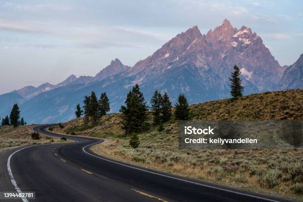 Winding Road Climbs Hillside In Front Of The Tetons Stock Photo - Download Image Now