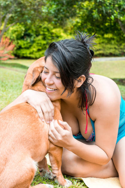 Smiling Latina woman and dog at public park.