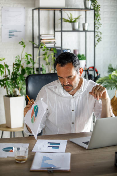 istock Businessman looking at charts and graphs on documents while working at his desk 1394483762
