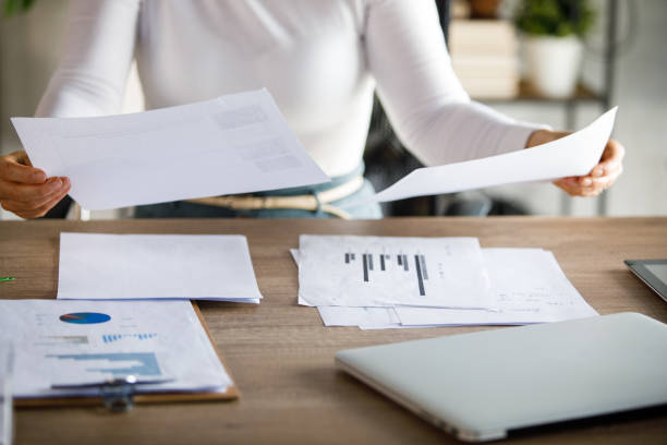 istock Midsection of businesswoman analyzing various documents at her desk 1394483980