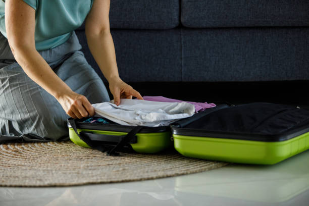 istock Woman arranging clothes in a suitcase when packing for a vacation 1394485400