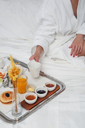 Breakfast tray in bed in luxury resort. Breakfast in bed with fruits, pancakes, cereals, coffee and juice on a tray.