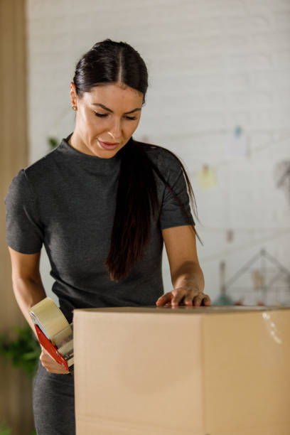 istock Young female entrepreneur taping shut the box with customer's order 1394486144