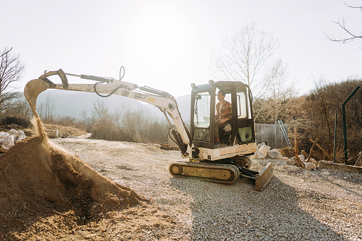 Photo of a man operating an excavator while working on a project at the construction site.