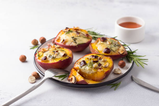 melocotones al horno con queso azul, avellanas, romero, servidos con miel sobre fondo gris claro - dessert grilled peaches peach fotografías e imágenes de stock