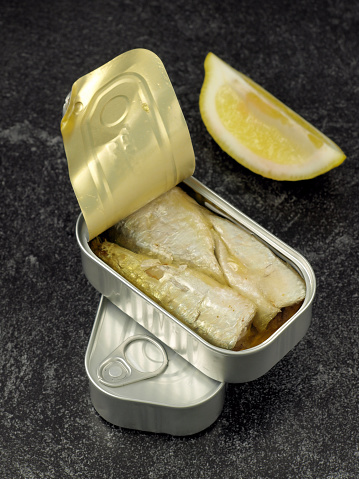 Canned sardines in olive oil and chopped lemon isolated on dark background.
