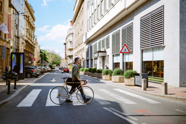 Commuter pushing his vintage road bicycle on the crosswalk, getting to work.