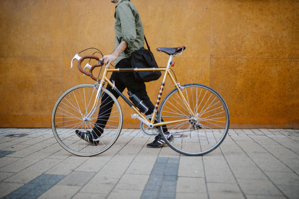commuter pushing his bicycle on the way to work Commuter pushing his vintage road bicycle on the pavement, getting to work. hipster bike stock pictures, royalty-free photos & images
