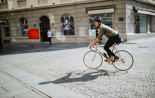 Mid aged man commuting on his vintage road bicycle through the city streets.