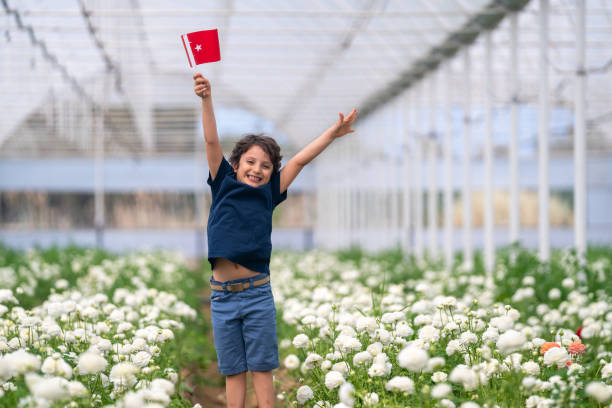 Photo of elementary aged boy holding Turkish flag and running in flower garden stock photo