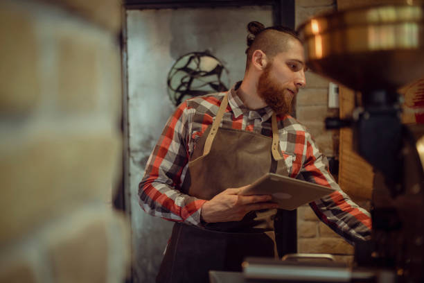 istock The waiter with the apron uses a digital tablet while standing in the cafeteria pantry. 1394500457