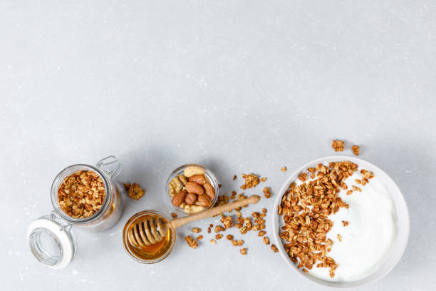 tigela caseira de granola de aveia no fundo cinza ligth. conceito saudável de café da manhã. sementes orgânicas de aveia, amêndoa e girassol. lay plano, design ameaçador, vista superior - granola oatmeal cereal fruit - fotografias e filmes do acervo