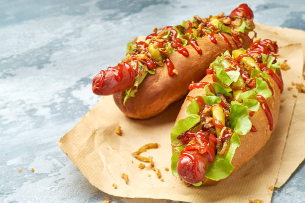 Two delicious hotdogs on craft paper over concrete background stock photo