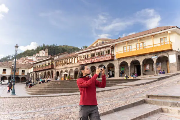 Tourist taking a photo in the main square of Cuzco