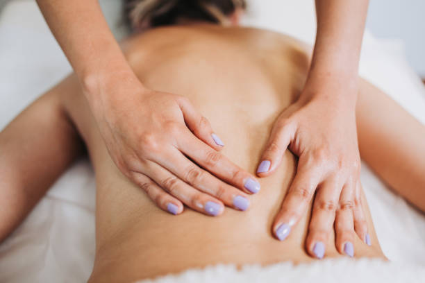 istock Unrecognizable therapist making a lower back massage to a face down female patient. Wellness center spa. 1394508923