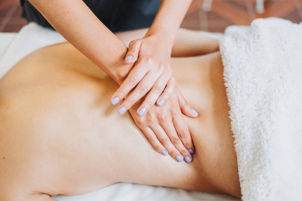 istock Unrecognizable therapist making a lower back massage to a face down female patient. Wellness center spa. 1394508967