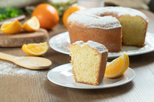 close up piece of moist orange fruit cake on plate with orange slices on wooden table. delicious breakfast, traditional english tea time. orange cake recipe. - fruitcake cake fruit dessert imagens e fotografias de stock