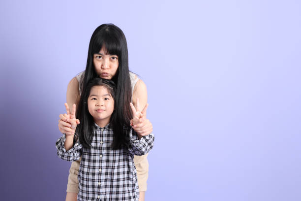The Asian family standing on the purple background with happy smile.