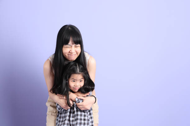 The Asian family standing on the purple background with happy smile.