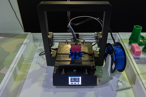3D printer is printing part from polymer at robot exhibition. Innovation technology business abstract.