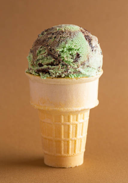 istock Mint Chocolate Chip Ice Cream Cone on a Brown Background 1394526235