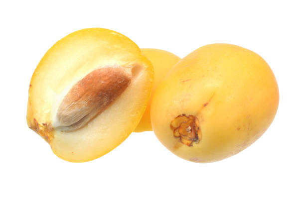 Ripe yellow dates fruits in cluster and half with stone closed up isolated on white