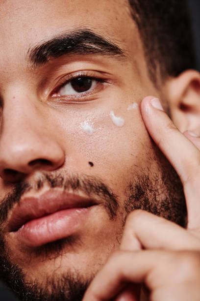 Young man applying cream on his face