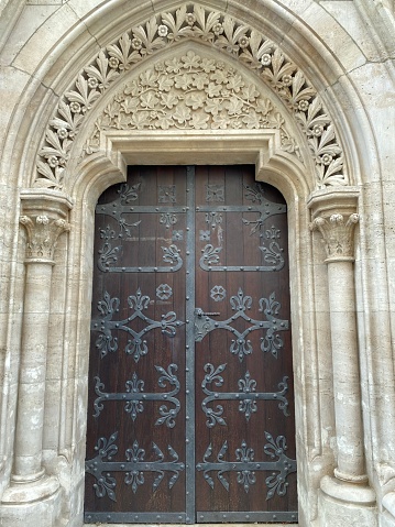 Huge wooden door with metal decoration and a beautiful stone full of carved in patterns archway