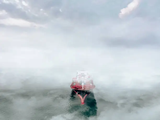 Photo of Aerial view of Container freight ship in transit in a foggy day.